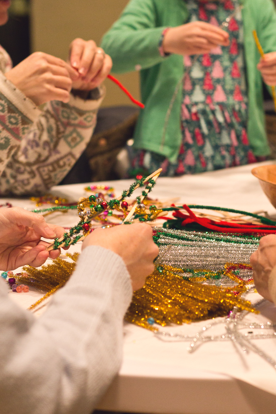 Table of people creating lollipop stick stars and decorating them.