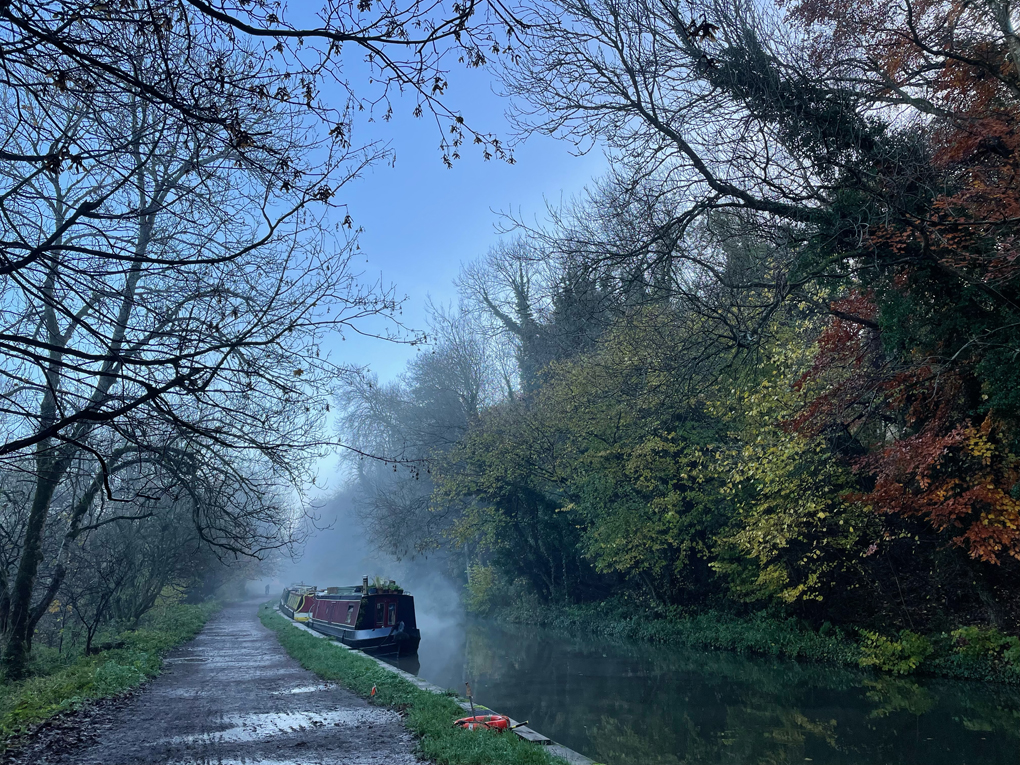 Muddy tow path and autumnal trees next to a canal