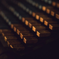 Dusty yellow and blue keys of an old, large, printmakers typewriting machine.