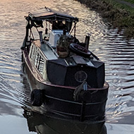 Sunset over a canal with a boat heading towards the bridge viewpoint