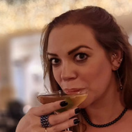 Lady drinking a martini in front of a big Christmas tree