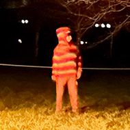 Night-time wassailers standing amongst apple trees