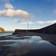 Reflection of a cloudy blue sky on the edge of Charlestown Harbour.