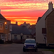 Photo taken at the end of my road, with a sky that looks like it's on fire, beautiful reds, oranges and even some purples.