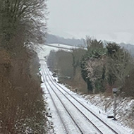 We see a picture of snow on railway tracks emerging from a bridge