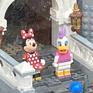 A bay window at the front of a shop containing a Lego theme park. There is a carousel, a train, a rollercoaster and a castle with Mickey and Minnie Mouse on the balcony.