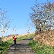 Woman running in the distance in a countryside landscape.