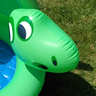 A green, stegosaurus-like paddling pool where the fin becomes a sun shield