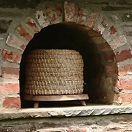 upon visiting a beautiful garden with a Mediaeval Monastery in Herefordshire we encountered a strange six foot wall with a roof and eight cubby holes in which the beehives (upturned basket domes) were housed. The bees form naturally curved honey combs inside the baskets. To collect the honey the bees are either killed or made homeless in the process. A shocking and sad fact! Each year the bee-keeper needs to start again by collecting a new wild swarm. Poor bees!!!