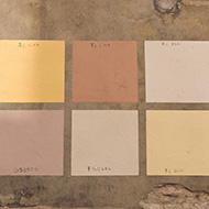 6 subtle paint test squares on exterior wall in historic town.