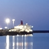 Fishguard Ferry having docked at dusk with all the lights on reflected on the sea with a promontory of land to its left. Next stop Ireland! An inviting sight in Goodwick harbour on a warm summer evening.