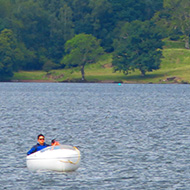 We see a small boat on lake Windemere framed by the mountains