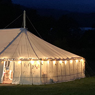 Picture of the glowing wedding marquee next to Derwentwater with storm clouds brewing above it.