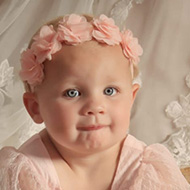 My granddaughter was a Flower Girl at her uncle’s wedding, she is sitting on the floor in a gorgeous pale pink dress, whilst sporting  a rather mischievous look on her pretty  face. The bride’s lace train  is the backdrop to the image.