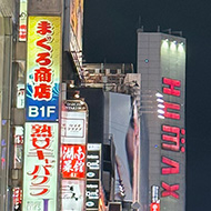 Tokyo street with many people and buildings with neon signs.