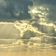 Sunset over Lee Bay with god rays and the sun highlighting the clouds in gold.