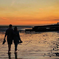 Two people walking on beach in sunset