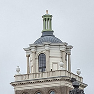 A town square. Edwardian era buildings surround car park and a statue of The Queen Mother.