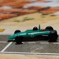 Three plastic cars approach a tight corner of a cardboard track.