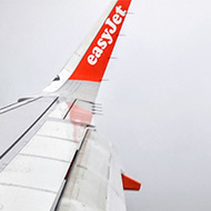 Image of the wing of the easyjet plane with Birmingham factories visible below the clouds.