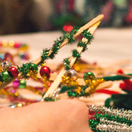 Table of people creating lollipop stick stars and decorating them.