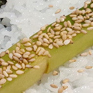 A half made cucumber hosomaki on a sushi rolling mat ready to be rolled.