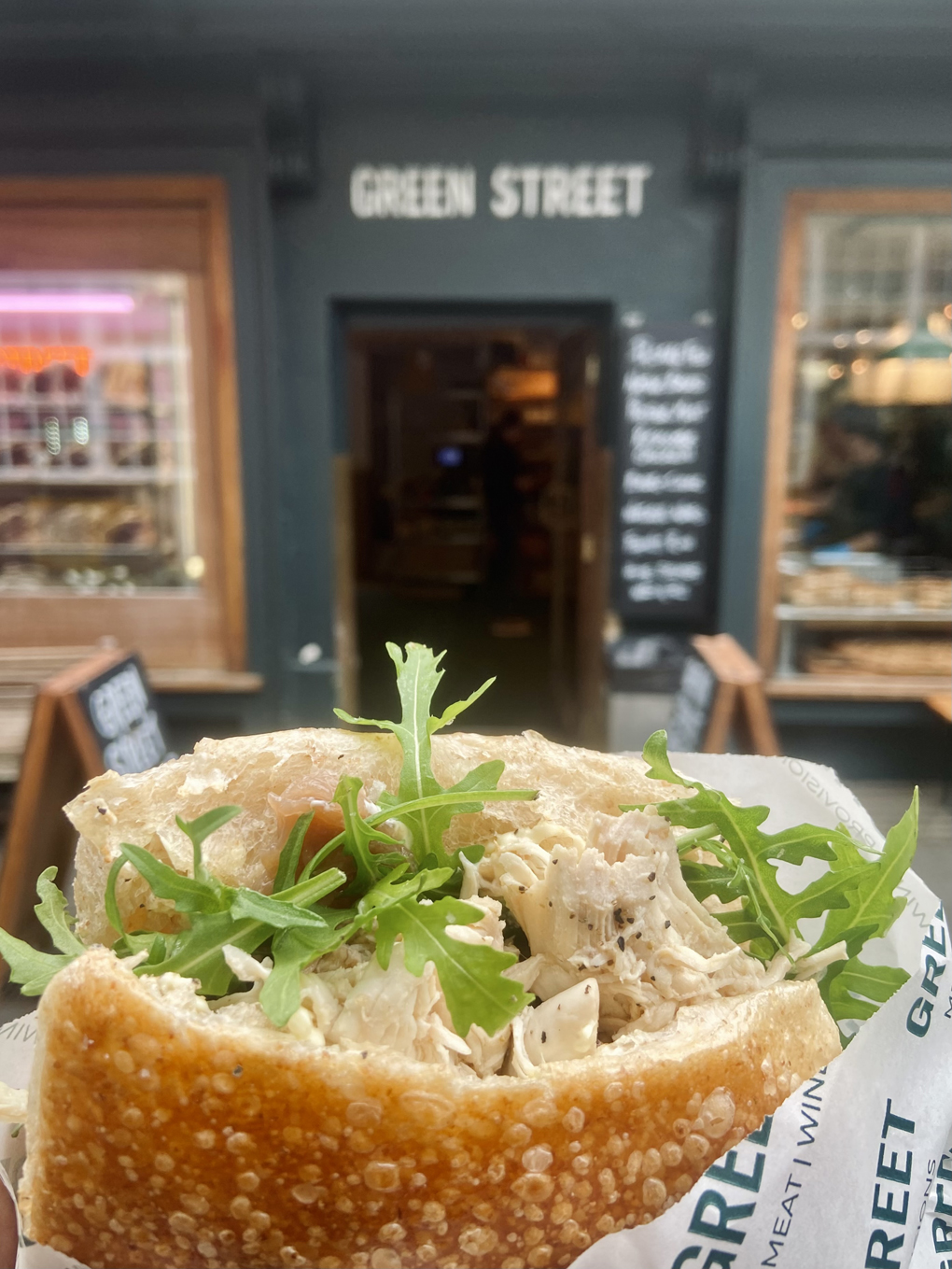 Chicken and rocket ciabatta bap photographed against butcher's green shop front on Green Street, Bath