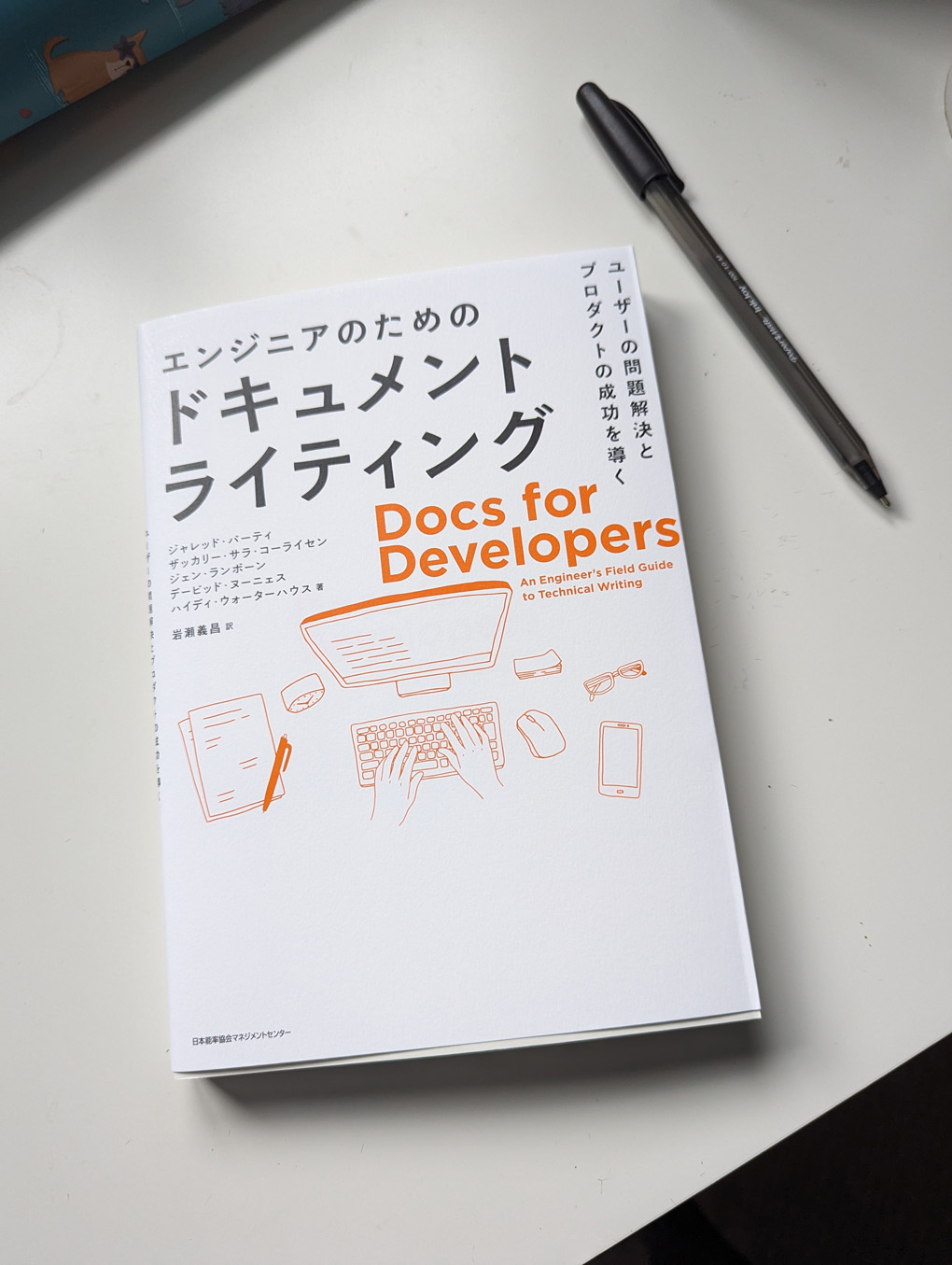 A book on a desk. The front cover is covered in Japanese text with the only words in English: Docs for Developers