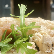 Chicken and rocket ciabatta bap photographed against butcher's green shop front on Green Street, Bath