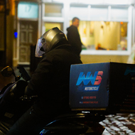 A delivery driver stationary on his scooter, waiting for their next delivery app job.