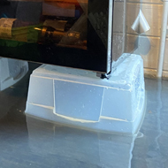 A small chest freezer and a wine fridge placed on top of plastic boxes to keep the white goods out of two inches of flood water in a log cabin.