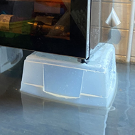 A small chest freezer and a wine fridge placed on top of plastic boxes to keep the white goods out of two inches of flood water in a log cabin.