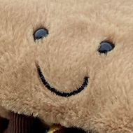 A soft toy pain au chocolat with a smiley face, sitting on a length of chain fence which is covered in padlocks.