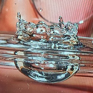 Drop of water falling into a glass of water in front of a bespectacled man