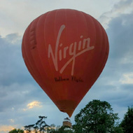 Hot air balloon hitting trees at the edge of a field