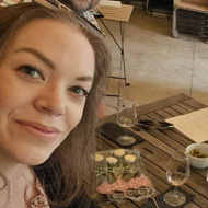 Adults around a table eating food and drinking wine