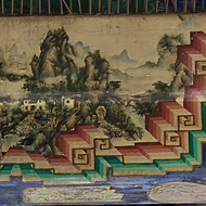 Standing inside a japanese-style pagoda with red pillars we see the roof, which has paintings onthe beams of mountains, lakes, flowers and people on it. Heading off into the distance is a path with overgrown grass on each side and a security gate at the end, which is closed.