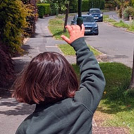 A young girl in school uniform running down the road