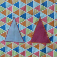 Multi coloured cot quilt featuring triangles.