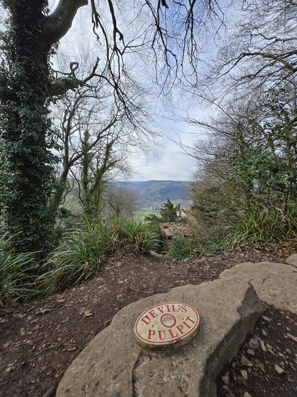 A countryside view from a view point, the name of the view point 'Devil's Pulpit' is on a sign on the ground