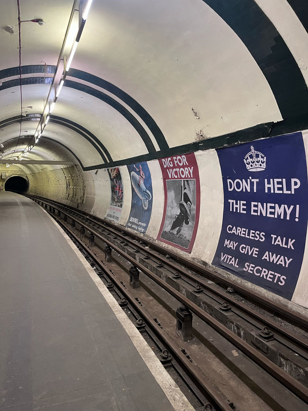 An empty London Underground platform with large mocked up posters from the World War 2 era