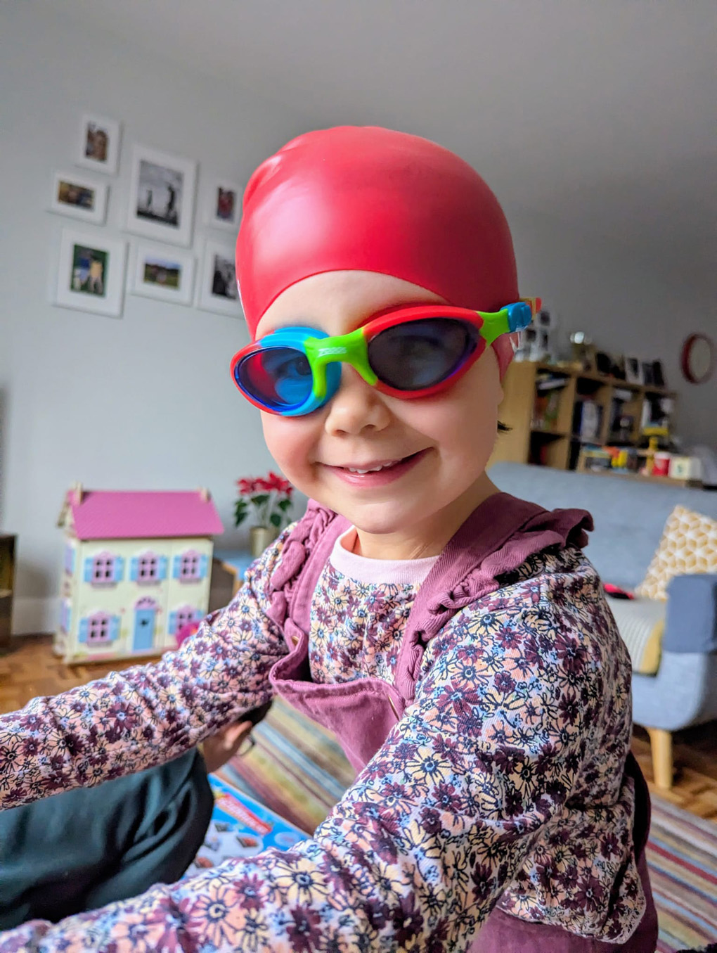 Child in multicoloured swimming goggles wearing a swimming cap
