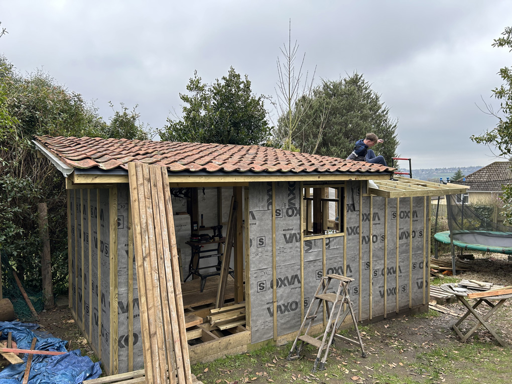 Part-built shed in a garden under a heavy sky.