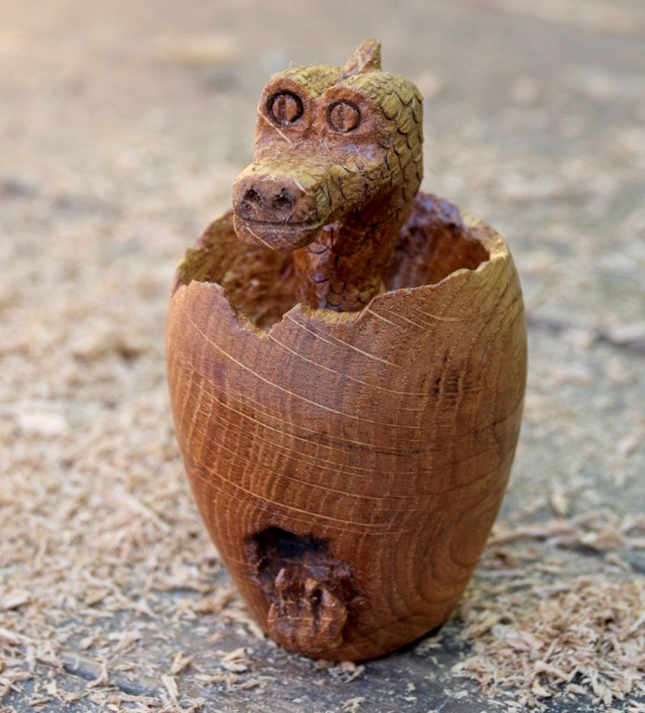 Made from polished oak the images shows a baby dragon's head emerging from an egg.