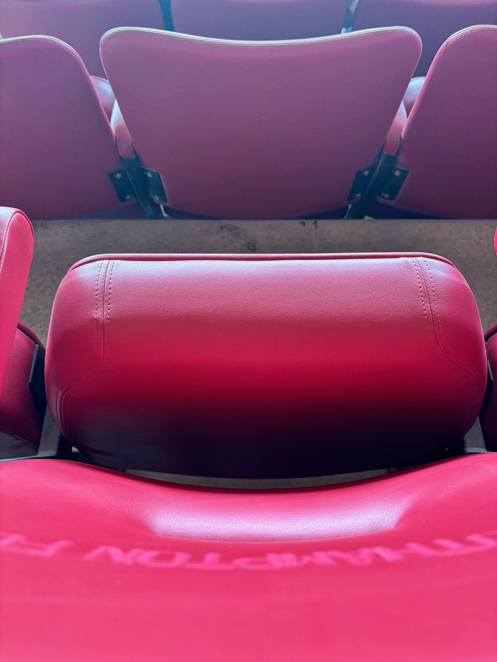 Looking down at some bright red padded seating in a sports stadium