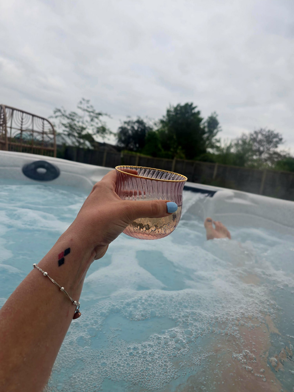 Hand holding a drink in an outdoor bath