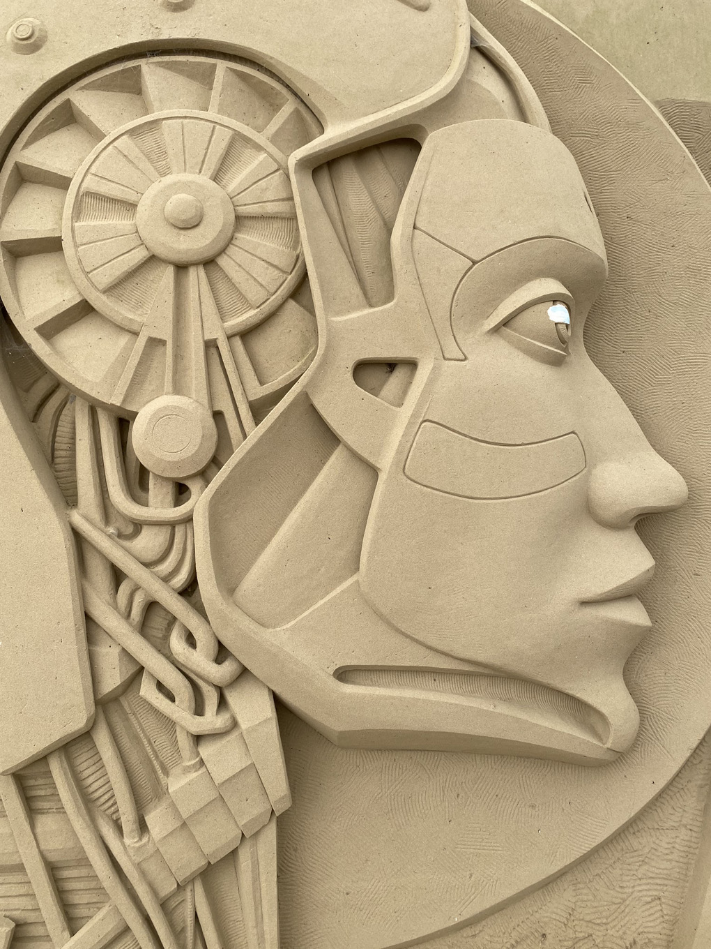 An automaton's head carved out of sand.