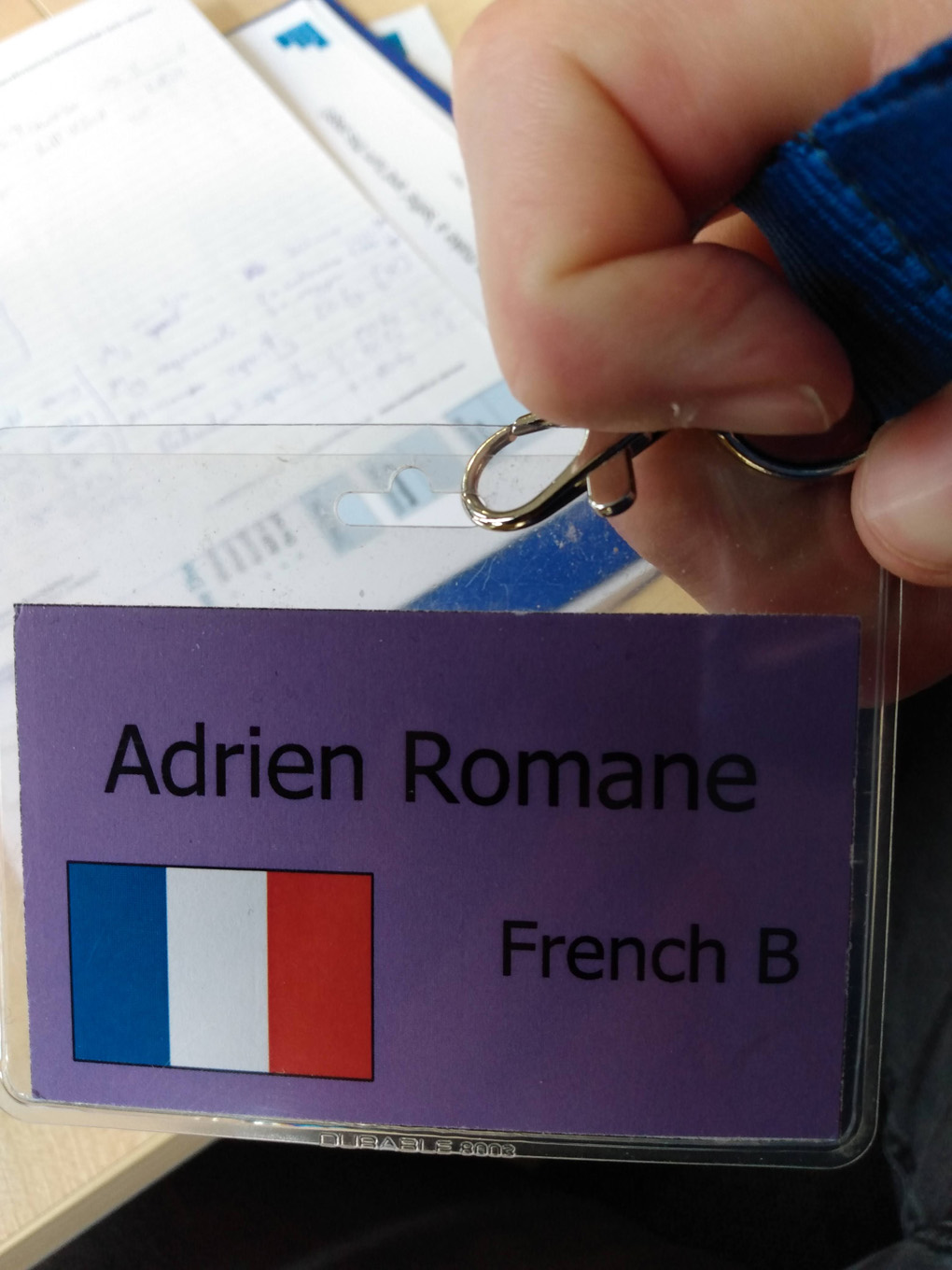 A lanyard has the French flag and the name Adrien Romane on it