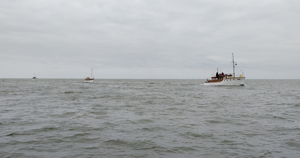 Three historic Little Ships in convoy, on a grey sea, under a grey sky.