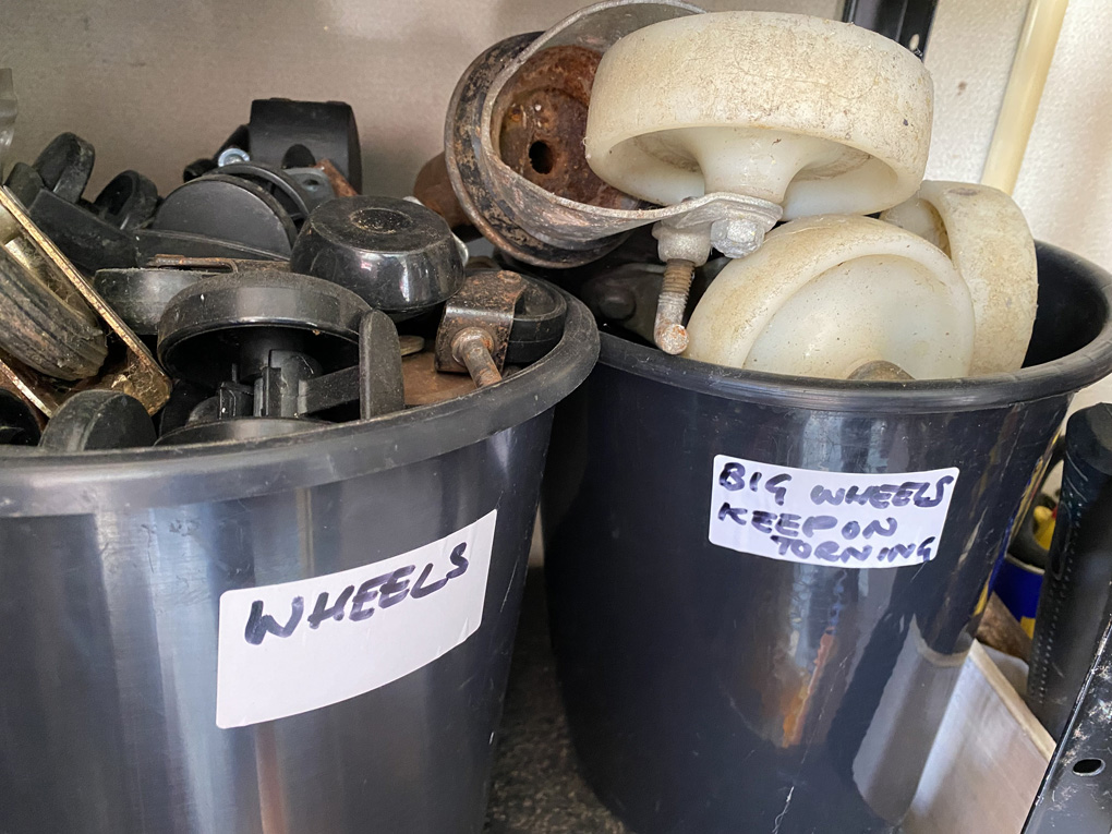 Two black buckets of wheels and casters, one labelled 